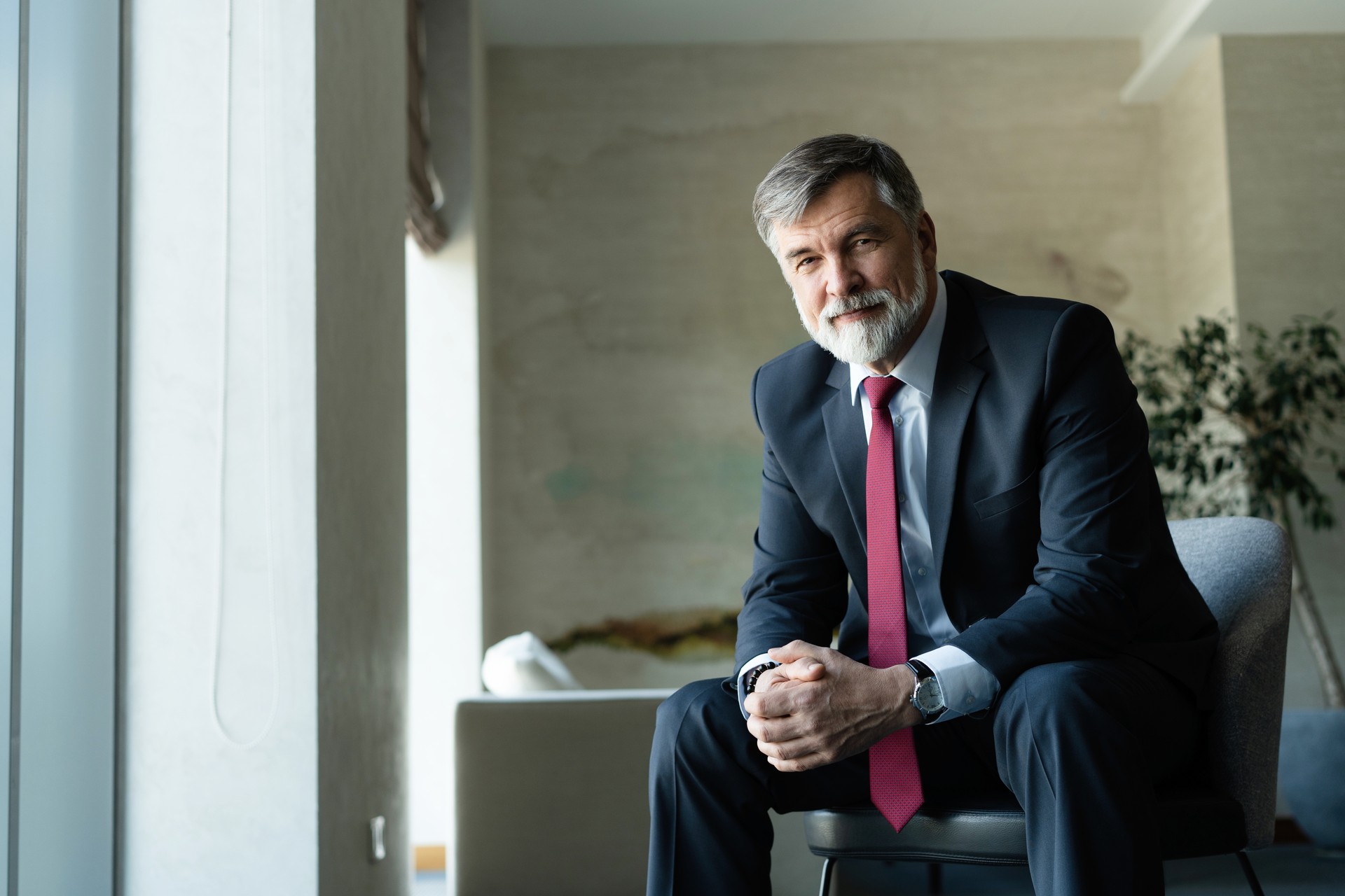 Positive successful mature businessman sitting in armchair in modern office